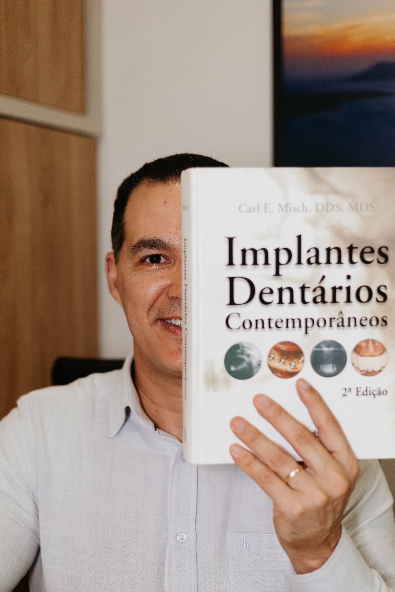 Dentista com livro Implantes Dentários Contemporâneos